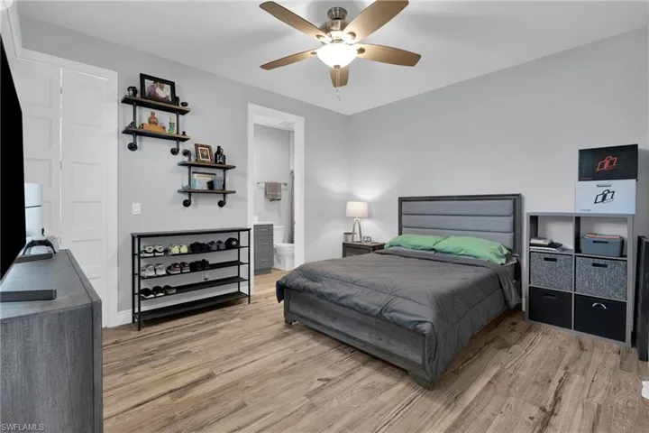 Bedroom featuring light wood finished floors, ceiling fan, and connected bathroom