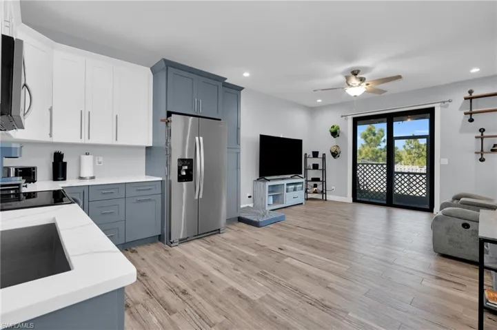 Dual tone kitchen featuring dual tone cabinetry, stainless steel appliances, open floor plan, light wood-type flooring, and ceiling fan