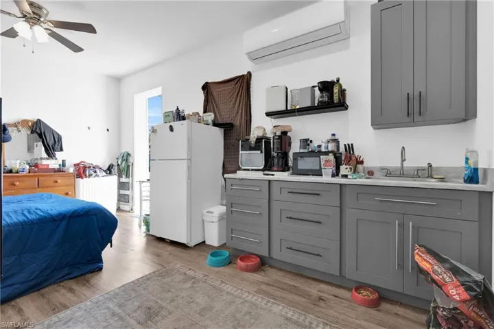 Kitchen with gray cabinets, freestanding refrigerator, light wood-style floors, and ceiling fan