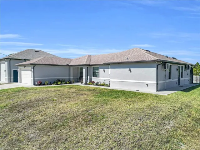 Ranch-style house featuring a front yard, an attached garage, stucco siding, and driveway