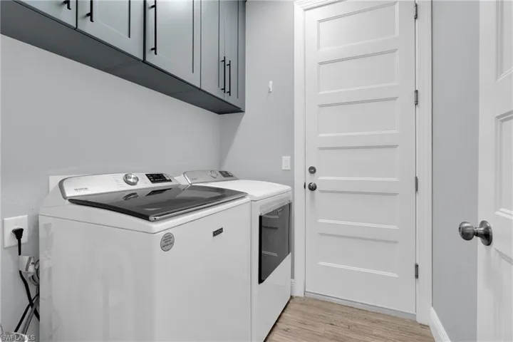 Laundry room featuring cabinet space, light wood-type flooring, and independent washer and dryer