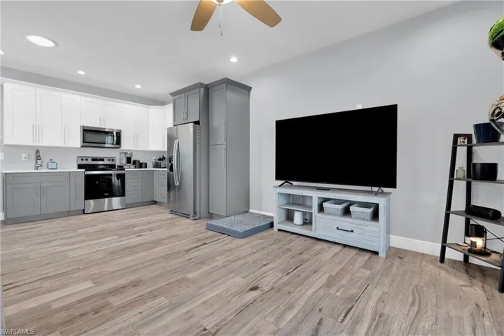 Dual tone kitchen featuring stainless steel appliances, two tone color scheme, light countertops, ceiling fan, and light wood-style flooring
