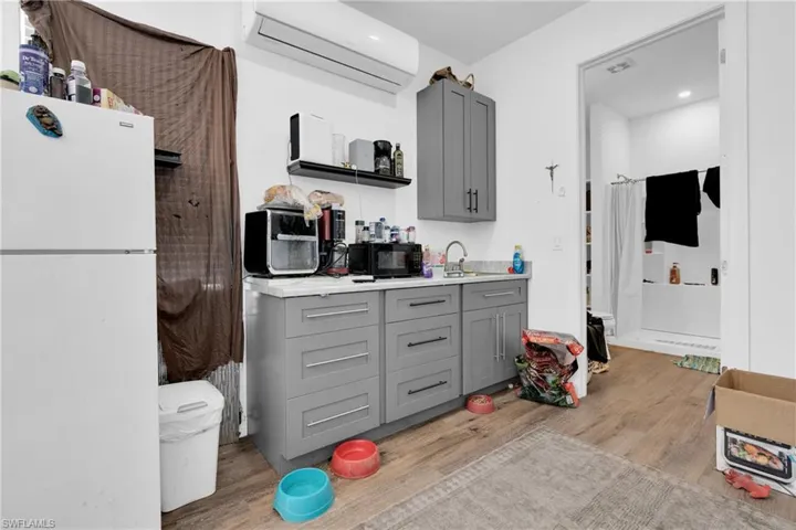 Kitchen featuring gray cabinetry, freestanding refrigerator, light countertops, light wood-style flooring, and open shelves