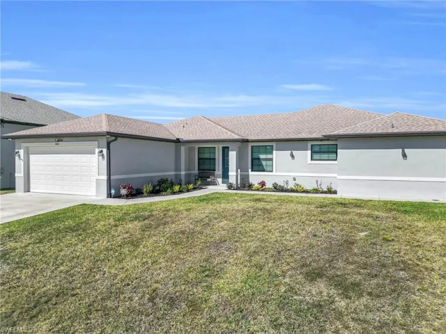Ranch-style home featuring a front lawn, stucco siding, an attached garage, and driveway