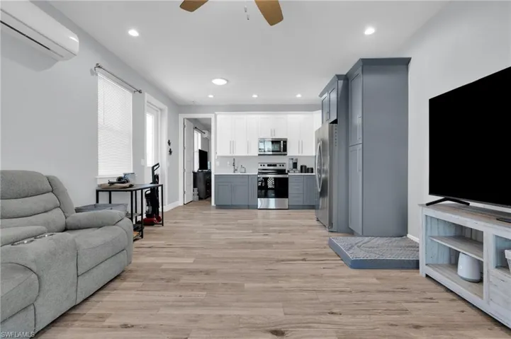 Living room with ceiling fan, light wood-style floors, and recessed lighting