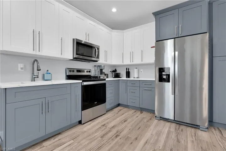 Kitchen with dual tone cabinets, stainless steel appliances, light wood-style floors, and recessed lighting