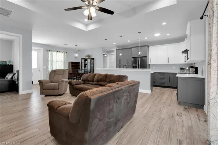 Living room with ceiling fan, light wood finished floors, recessed lighting, and a raised ceiling