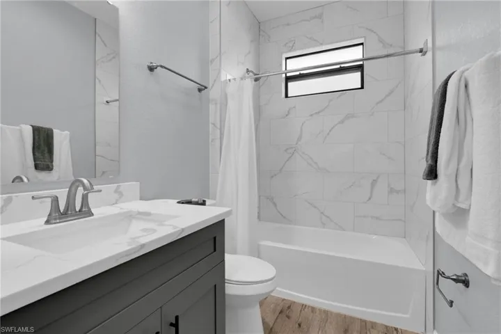Bathroom featuring vanity, shower / bath combination with curtain, and light wood-style flooring