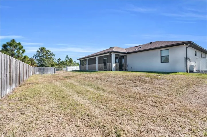 Rear view of property featuring a sunroom, a fenced backyard, and stucco siding