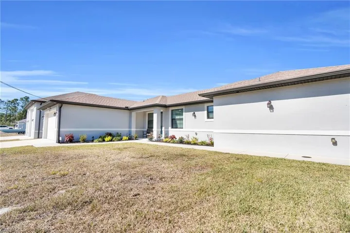 Prairie-style home featuring a front yard, an attached garage, stucco siding, and driveway