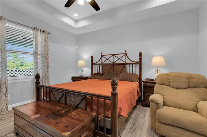 Bedroom with light wood finished floors, a ceiling fan, recessed lighting, and a raised ceiling