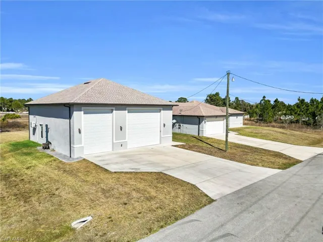 View of property exterior featuring stucco siding, roof with shingles, a lawn, and a garage