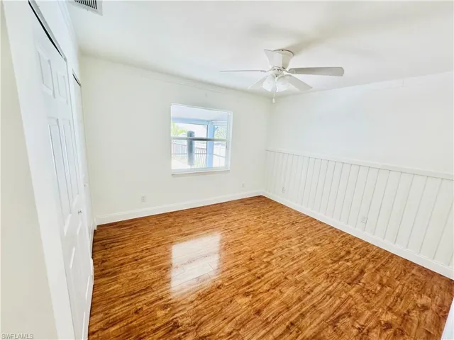 Unfurnished bedroom featuring a closet, wood finished floors, ornamental molding, and a ceiling fan