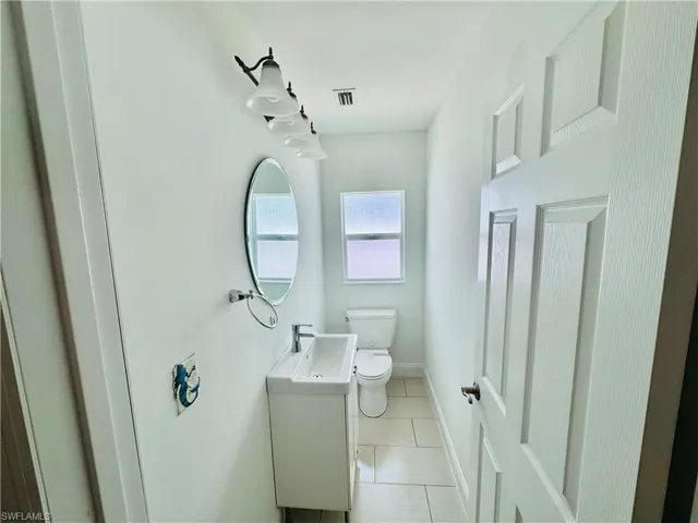 Half bath with tile patterned flooring and vanity