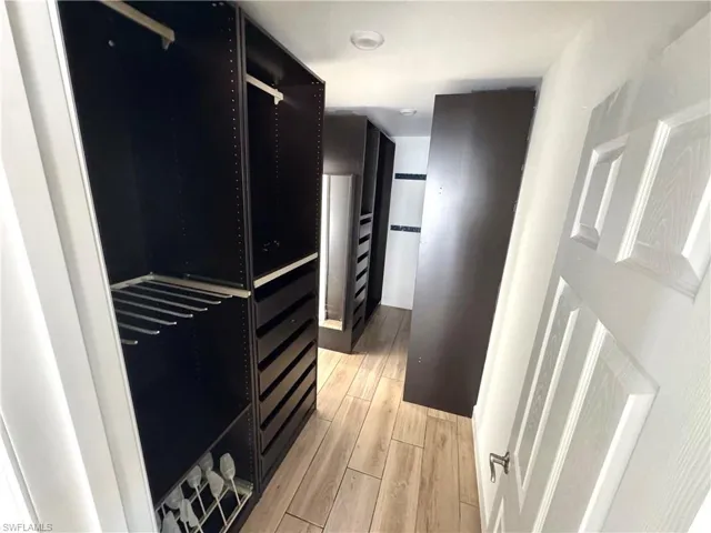 Walk in closet with light wood-type flooring