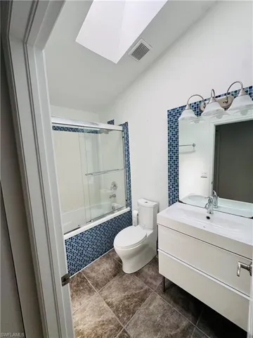 Full bath with a skylight, tiled shower / bath combo, vanity, and tile patterned floors