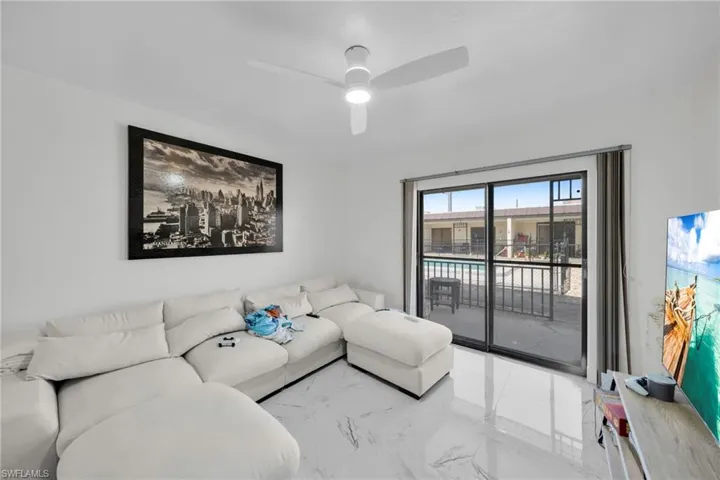 Living area featuring ceiling fan and light marble finish flooring