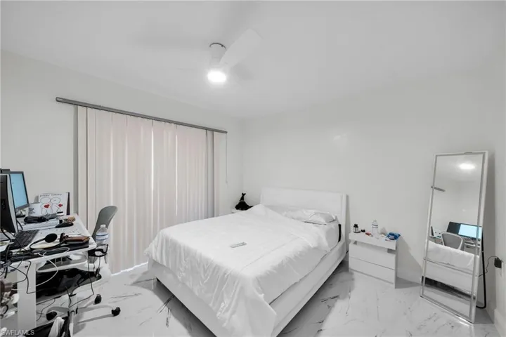 Bedroom with a desk, a ceiling fan, and light marble finish flooring