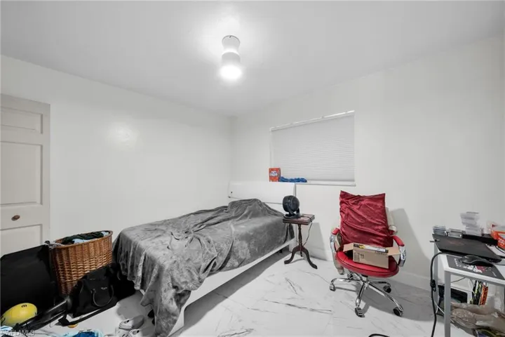 Bedroom featuring baseboards and light marble finish floors