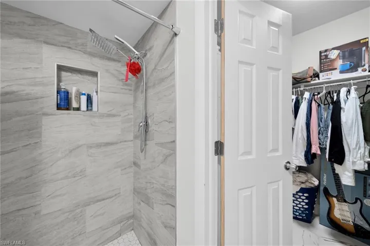 Full bathroom featuring a marble finish shower and a spacious closet