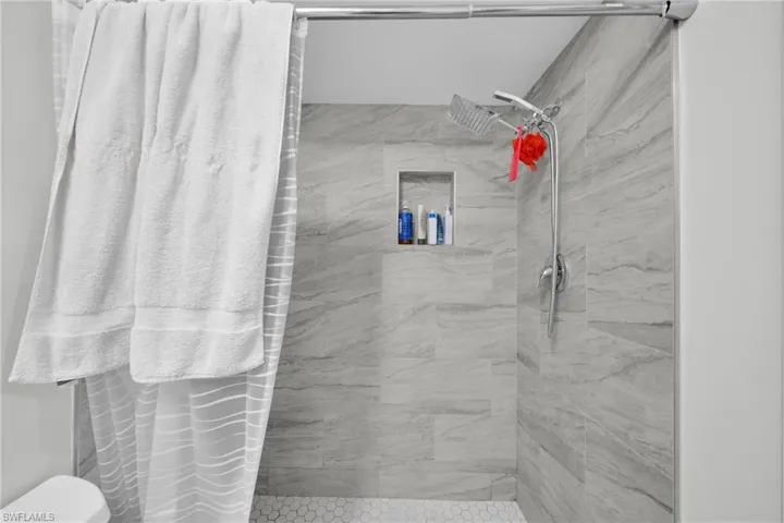 Bathroom featuring a marble finish shower and toilet