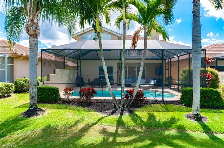 Rear view of house with a sunroom, a lawn, an outdoor pool, stucco siding, and glass enclosure