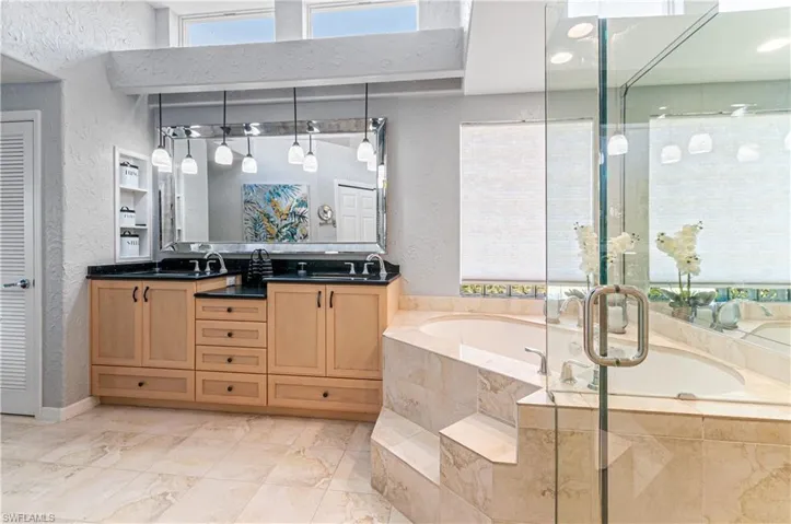 Full bathroom featuring a textured wall, double vanity, a garden tub, and a shower stall