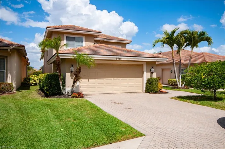 View of front of property with decorative driveway, an attached garage, a front lawn, stucco siding, and a tile roof