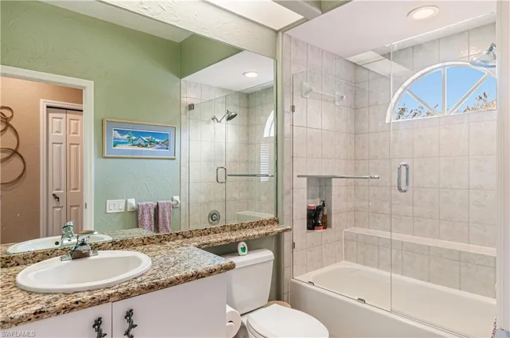 Full bathroom with vanity, a textured wall, and combined bath / shower with glass door