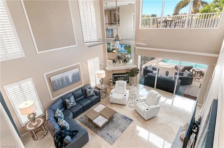 Living area featuring plenty of natural light, ceiling fan, a high ceiling, and a glass covered fireplace