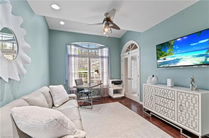 Sitting room with a textured wall, ceiling fan, dark wood-style flooring, and an office area