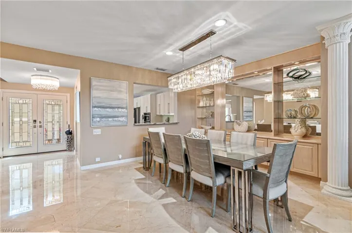 Dining room featuring ornate columns, french doors, light marble finish floors, and suspended lighting