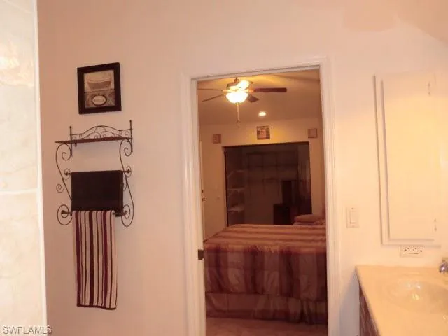 Bathroom vanity featuring a single basin sink and built-in medicine cabinet, opening to a room with a ceiling fan