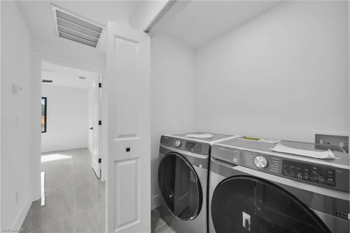 Laundry area with independent washer and dryer and light tile patterned flooring
