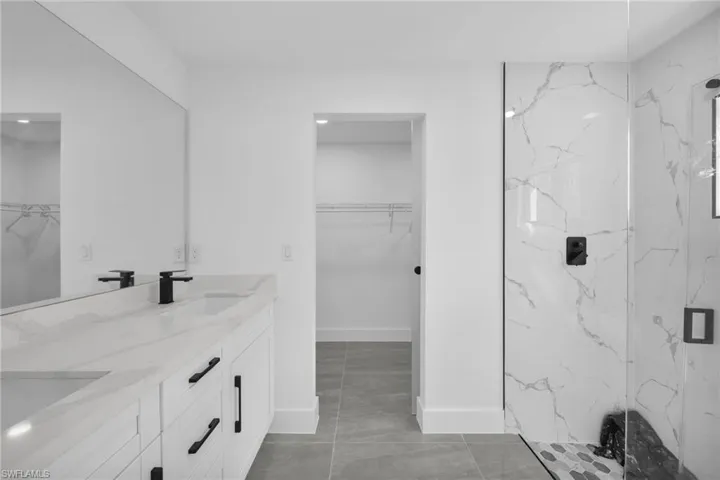 Full bathroom with a spacious closet, a marble finish shower, and double vanity