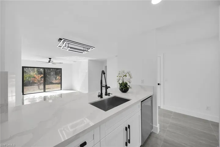 Bar with white cabinets, light stone counters, cooling unit, ceiling fan, and dishwasher