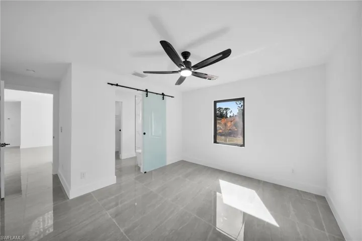 Unfurnished bedroom featuring a barn door and a ceiling fan