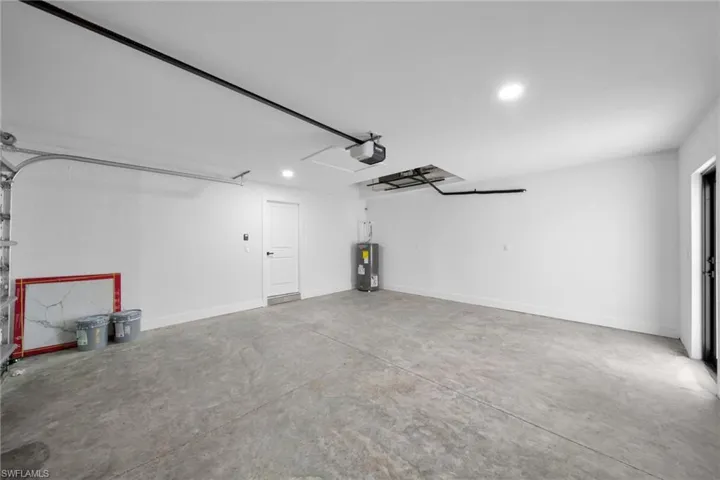 Garage featuring recessed lighting, water heater, and a garage door opener