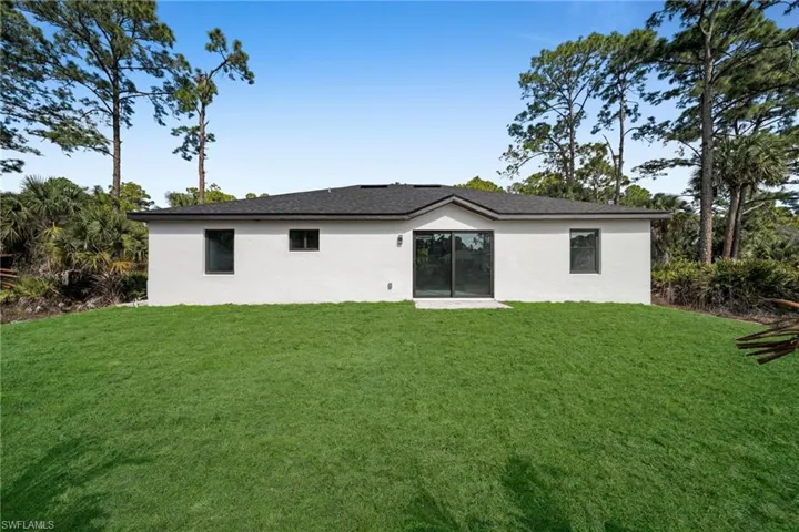 Back of property featuring a lawn and stucco siding