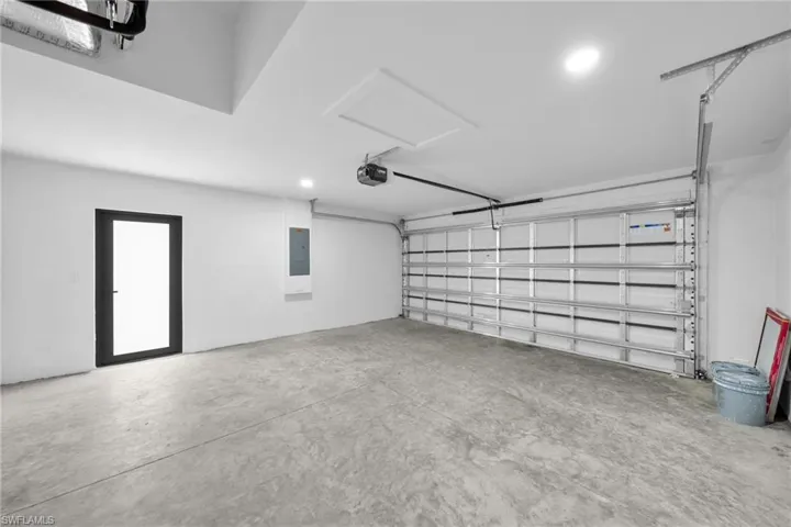 Garage featuring recessed lighting, electric panel, and a garage door opener