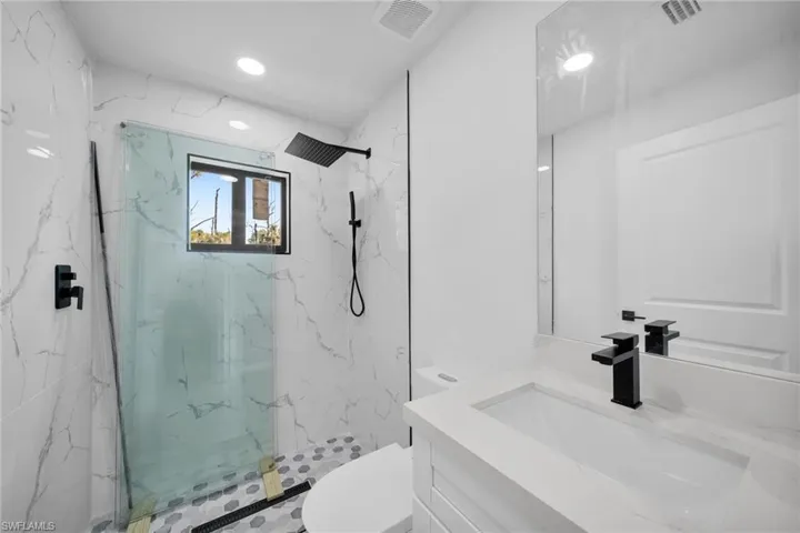Bathroom featuring vanity, a marble finish shower, and recessed lighting