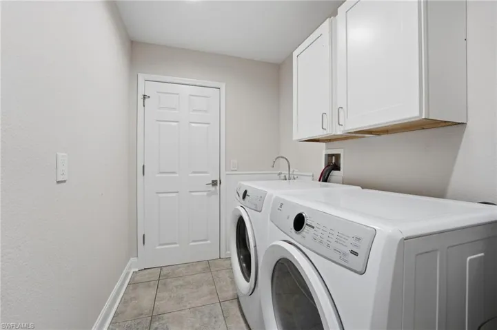 Laundry room with cabinet space, light tile patterned floors, and separate washer and dryer