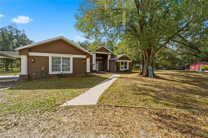 Ranch-style house featuring stucco siding, a front lawn, and a carport