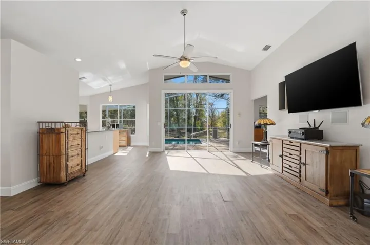 Living area with lofted ceiling, light wood-style flooring, ceiling fan, and a sunroom