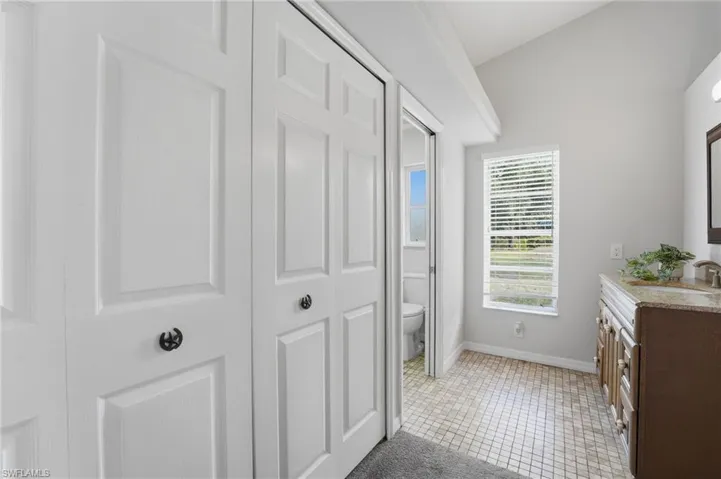 Full bathroom featuring a closet, vaulted ceiling, vanity, and light tile patterned floors