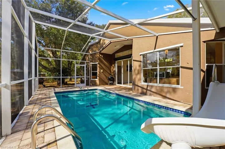 Outdoor pool with a patio, a sunroom, and glass enclosure