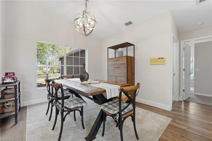 Dining space with light wood-type flooring, a chandelier, and vaulted ceiling
