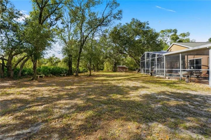 View of grassy yard with a sunroom and a lanai