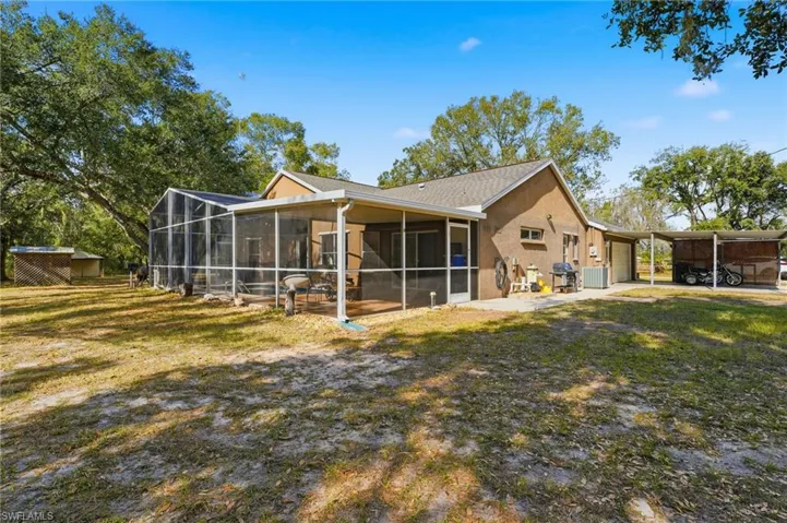Back of house featuring a yard, a sunroom, stucco siding, an outbuilding, and an attached garage