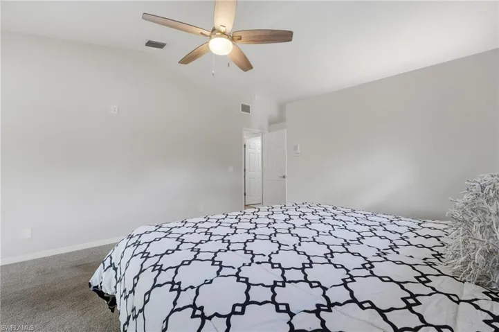 Bedroom featuring carpet, vaulted ceiling, and a ceiling fan
